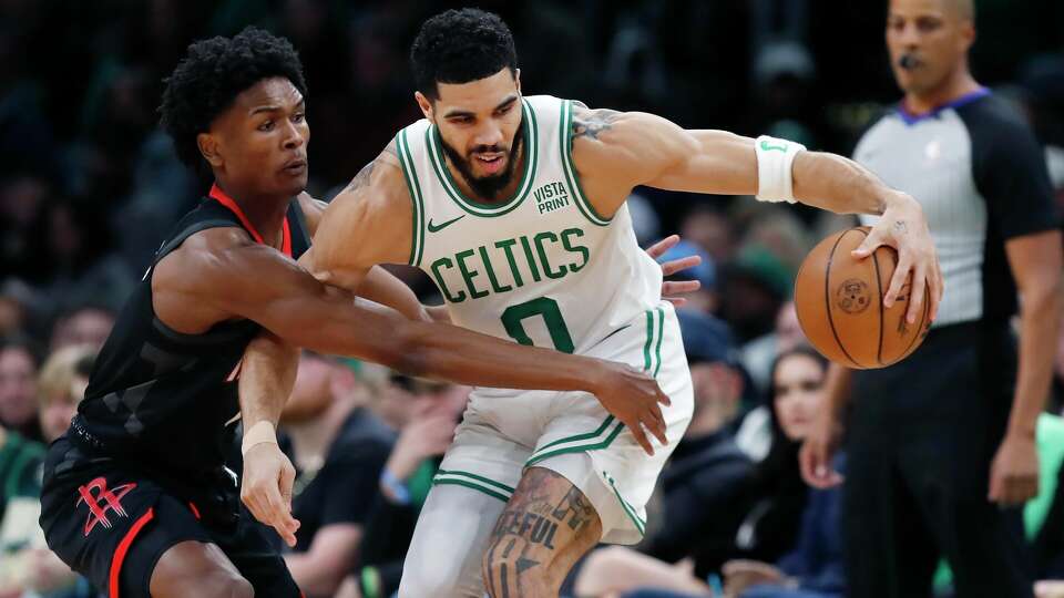 Boston Celtics' Jayson Tatum (0) keeps the ball away from Houston Rockets' Amen Thompson during the first half of an NBA basketball game, Saturday, Jan. 13, 2024, in Boston. (AP Photo/Michael Dwyer)