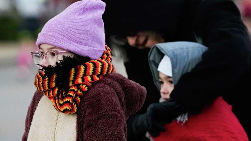 Georgia Andrews sinks her head down into her scarf and jacket as braces for wind in the 35-degree weather while watching runners race along Washington Avenue during the Chevron Houston Marathon, Sunday, Jan. 14, 2024, in Houston.