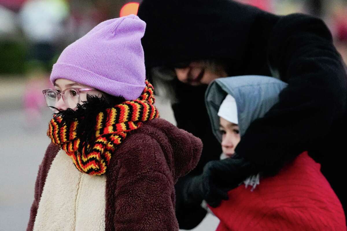 Georgia Andrews sinks her head down into her scarf and jacket as braces for wind in the 35-degree weather while watching runners race along Washington Avenue during the Chevron Houston Marathon, Sunday, Jan. 14, 2024, in Houston.