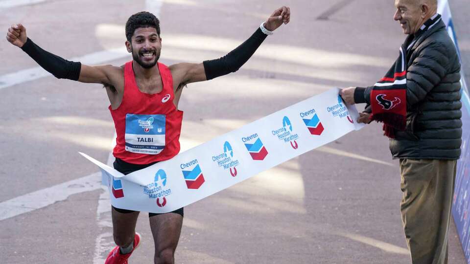 Zouhair Talbi runs past Mayor John Whitmire as he breaks the tape to win the men's Chevron Houston Marathon in a time of 2:06:39 on Sunday, Jan. 14, 2024 in Houston.