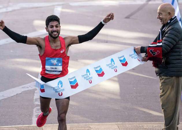 Zouhair Talbi runs past Mayor John Whitmire as he breaks the tape to win the men's Chevron Houston Marathon in a time of 2:06:39 on Sunday, Jan. 14, 2024 in Houston.