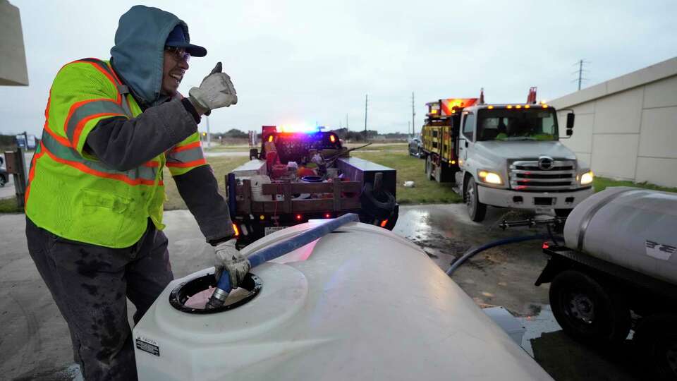 Edgar Tristan, with Jorgensen a contractor for TxDOT, signals a tank is full as he and other crew members re-fill with a brine solution at Mueschke Road and SH 99 Grand Parkway Monday, Jan. 15, 2024, in Cypress. The brine is sprayed as a pre-treatment to help prevent ice from bonding to the roadway.