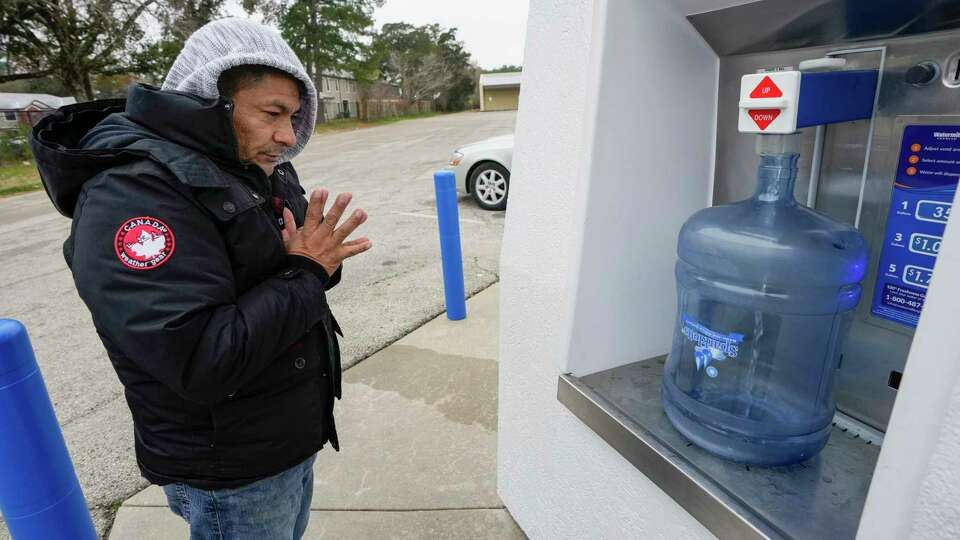 Hildo Espinoza rubs his hands together to keep them warm as he fills a water jug while preparing for a freeze as temperatures dropped below freezing on Monday, Jan. 15, 2024 in Conroe.