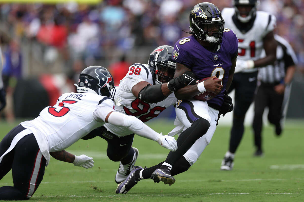 Lamar Jackson #8 of the Baltimore Ravens is wrapped up by Sheldon Rankins #98 of the Houston Texans during the first half at M&T Bank Stadium on September 10, 2023 in Baltimore, Maryland.