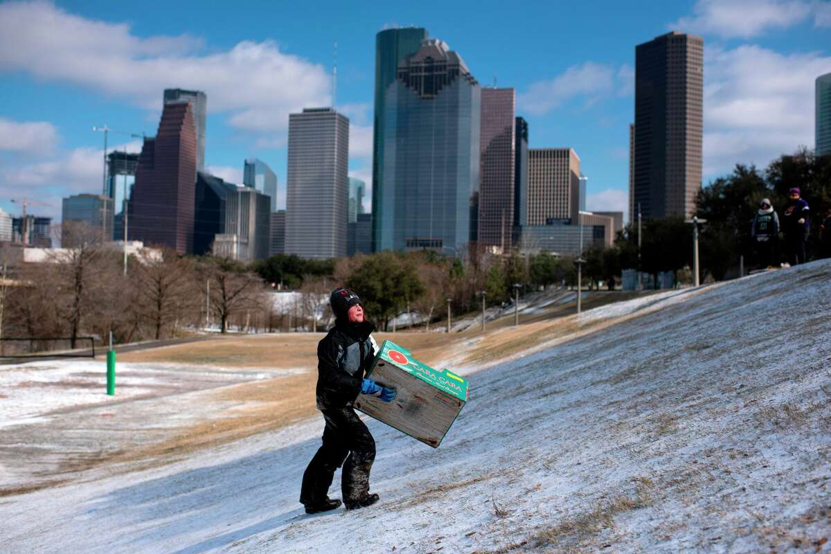 A boy walks up a snow covered hill after sledding down it in a box in Houston, Texas on February 15, 2021. Freezing conditions returned to Houston this week as a hard freeze descended on southeast Texas, leaving dangerous road conditions and breaking cold weather records on Tuesday, January 16, 2024.