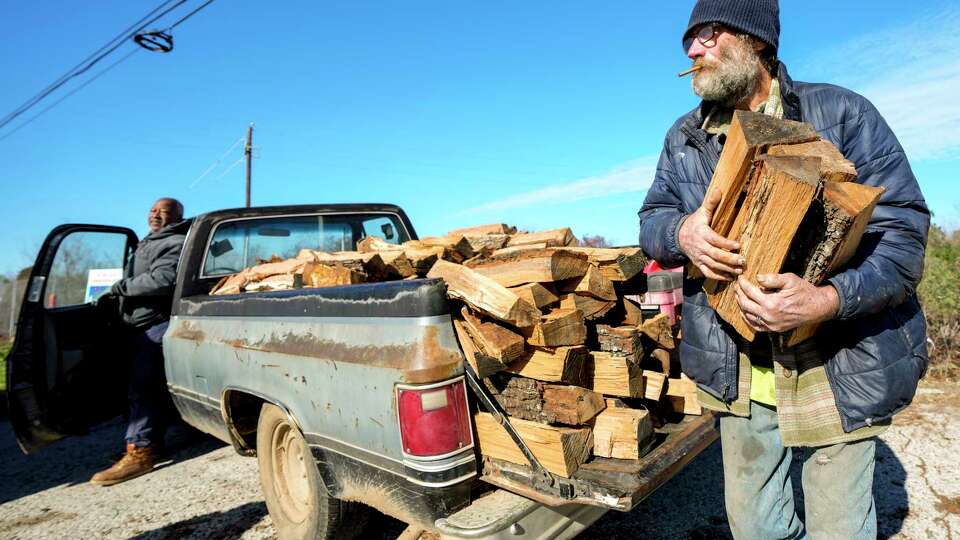 Forrest Austin grabs a stack of firewood from the back of a truck as he and Mickey Taylor sell wood along FM2920 on Tuesday, Jan. 16, 2024 in Spring.