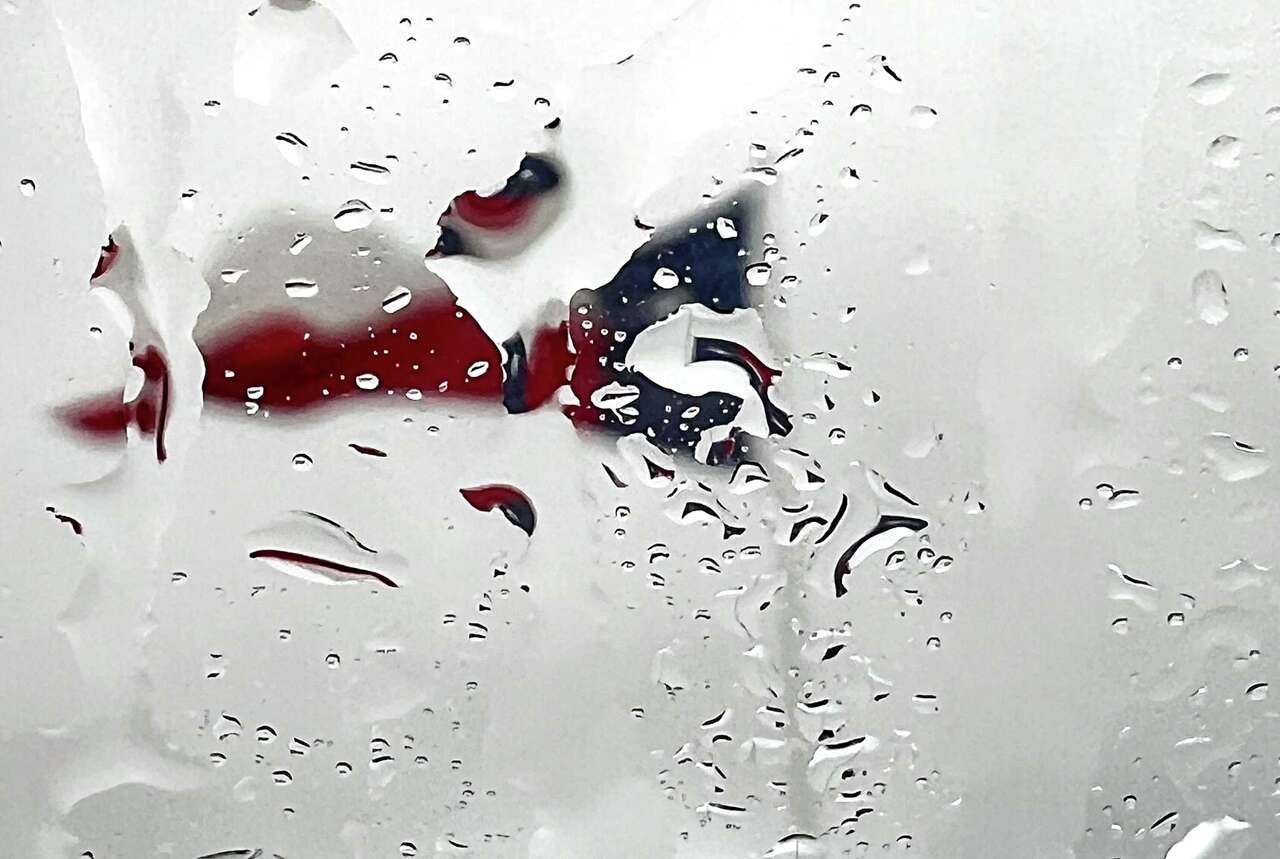 Rain drops distort a Texas flag at a car dealership on Monday, Jan. 22, 2024 in Houston.