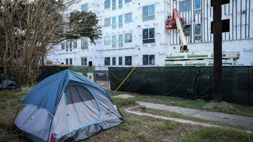 Construction continues across the street from a vacant lot where homeless people camp Tuesday, Jan. 30, 2024, in the Midtown neighborhood in Houston.