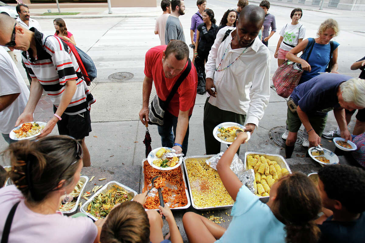 Volunteers with the Food Not Bombs, a homeless service organization, feed the homeless at the Houston Downtown Public Library courtyard, Sunday, July 1, 2012, in Houston.