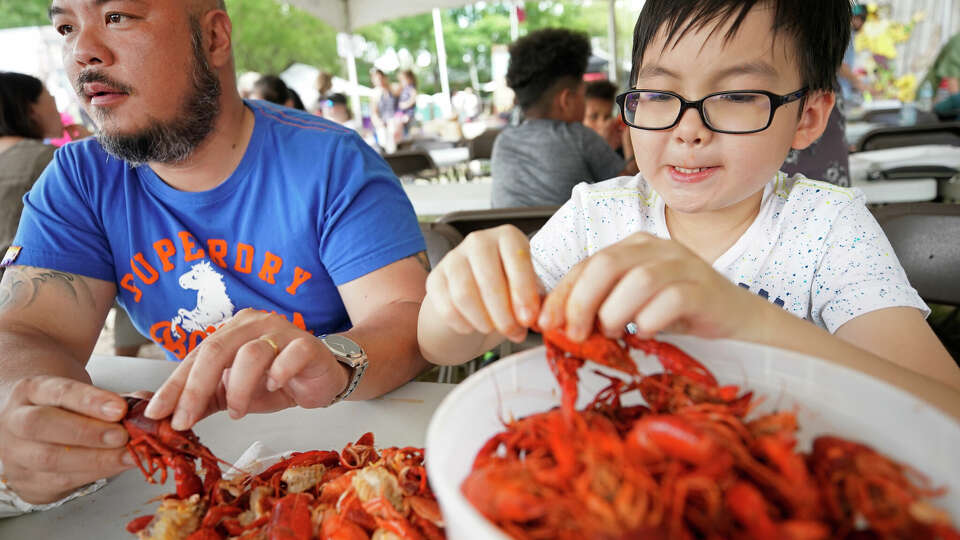 Thuc Vu of Katy and his son, Kha Vu, 9, eat crawfish during the 33rd annual Texas Crawfish and Music Festival in Old Town Spring Sunday, April 28, 2019, in Spring.