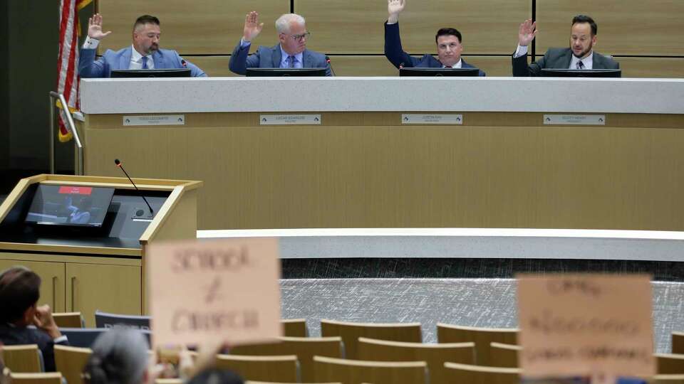 From left, Todd Lecompte, Lucas Scanlon, Justin Ray and Scott Henry raise their hands to vote against allowing religious councilors in the school district during the Cy-Fair ISD board meeting, held at the district administation building Monday, Mar. 4, 2024 in Cypress, TX.