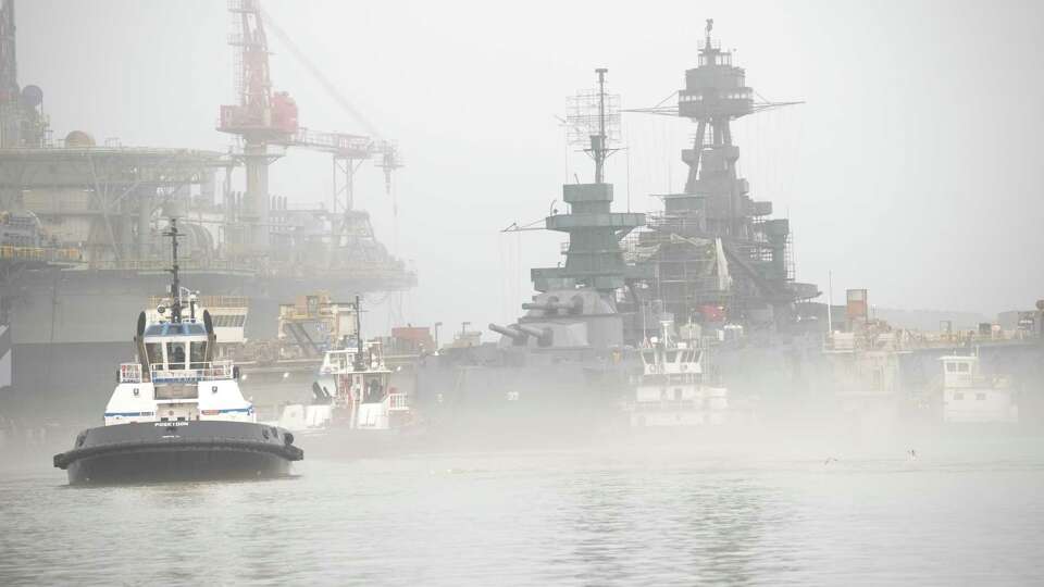 Tugboats move into position as Battleship Texas is removed from a drydock on Tuesday, March 5, 2024, in Galveston. After 18 months of hull restoration, the ship is ready to re-enter the water. Further restoration will continue at a nearby dock as part of a $70 million rehab of the historic battleship. Texas is the only remaining dreadnought battleship above water.