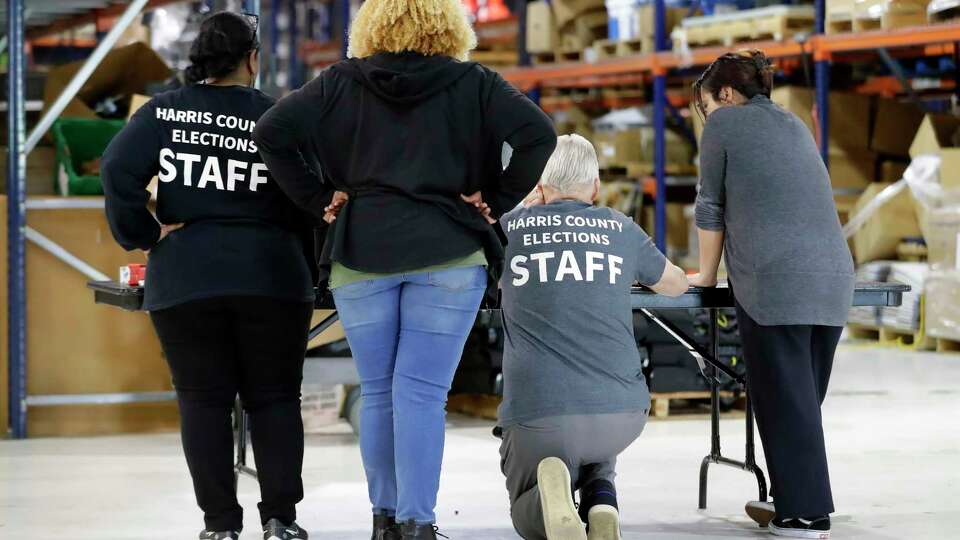 Harris County elections staff gather around a table in the warehouse as they check through laptop computers at the Election Technology Center Tuesday, Mar. 5, 2024 in Houston.