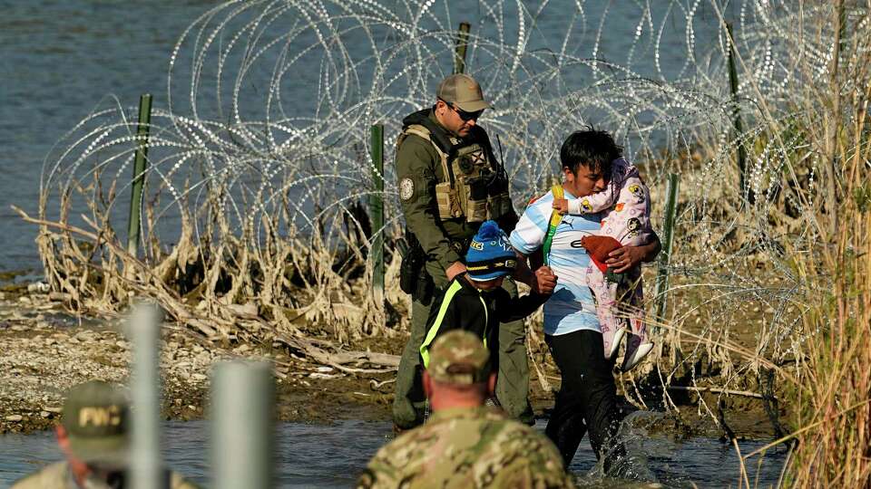 FILE - Migrants are taken into custody by officials at the Texas-Mexico border, Jan. 3, 2024, in Eagle Pass, Texas. The Supreme Court on Tuesday, March 12, 2024 extended a stay on a new Texas law that would empower police to arrest migrants suspected of illegally crossing the U.S.-Mexico border. The order puts the law on hold until at least Monday while the high court considers a challenge by the Justice Department, which has called the law an unconstitutional overreach.