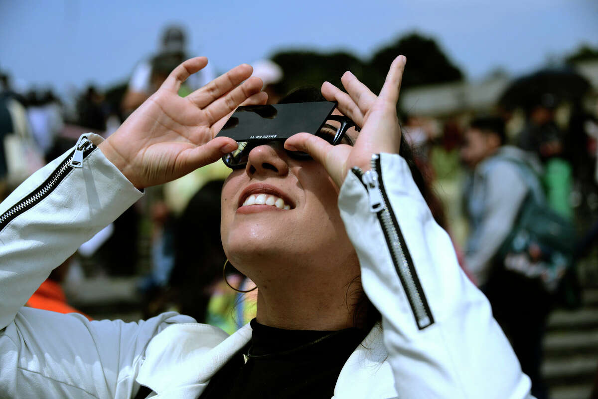 October 14, 2023, Mexico City, Mexico: A young woman is seen watching the Annular Solar Eclipse with special sun filter glasses at the National Autonomous University of Mexico (UNAM). (Photo by Carlos Tischler/ Eyepix Group) (Photo credit should read Carlos Tischler/ Eyepix Group/Future Publishing via Getty Images)