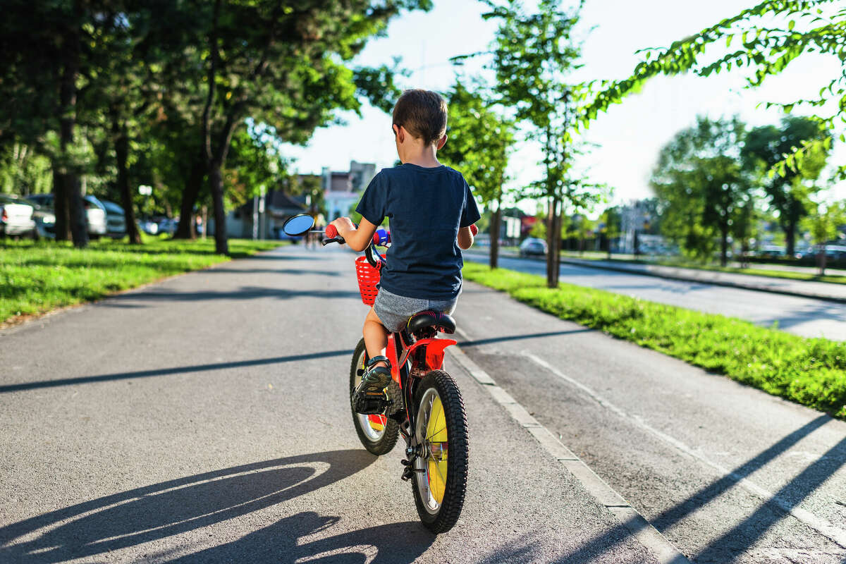 Child on a bicycle at asphalt road on sunset. 