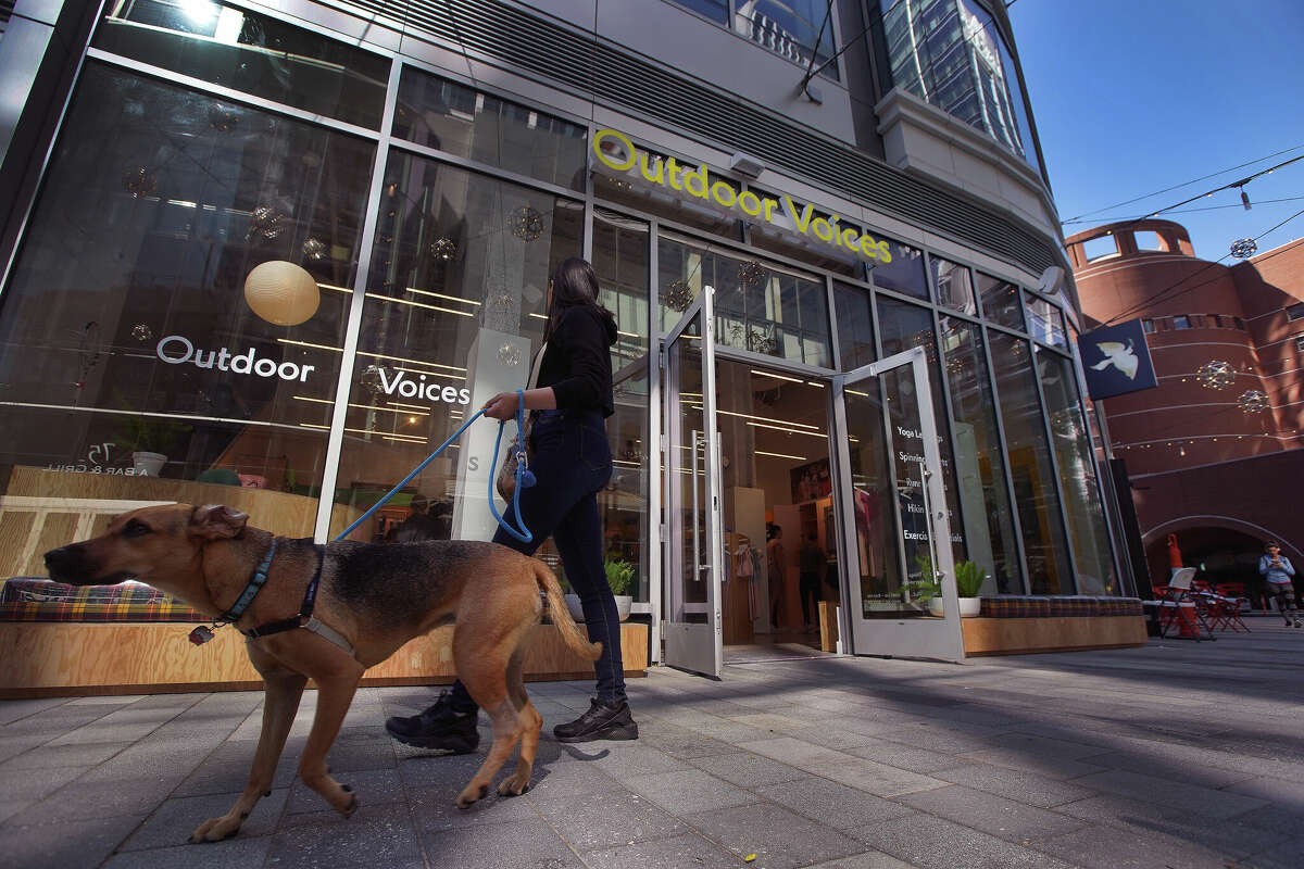 A pedestrian and dog pass by Outdoor Voices at One Seaport in Boston's Seaport District on July 12, 2018. 