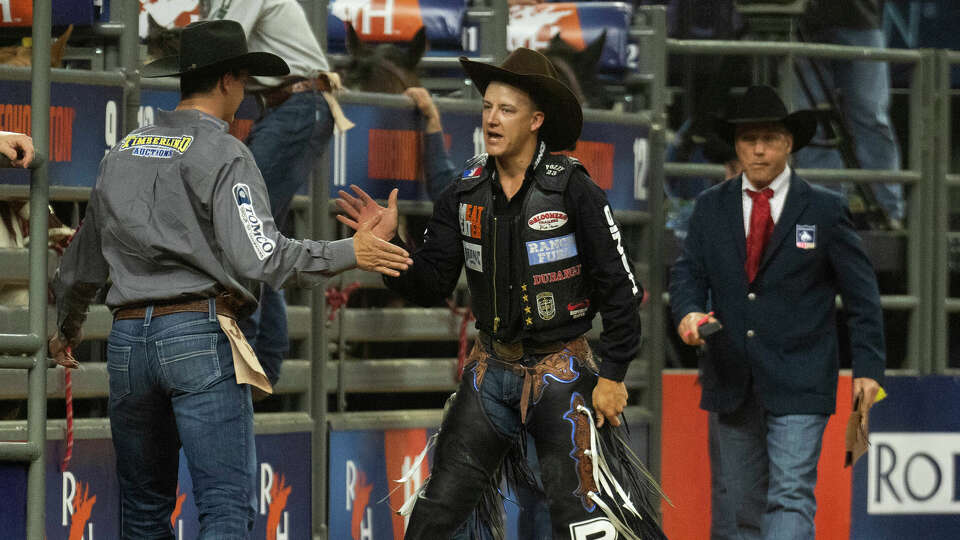 Zeke Thurston, center, gets a high-five after seeing his score in saddle bronc riding during the semifinal 2 of the Rodeo Houston at the Houston Livestock Show and Rodeo at NRG Park, Thursday, March 14, 2024, in Houston.