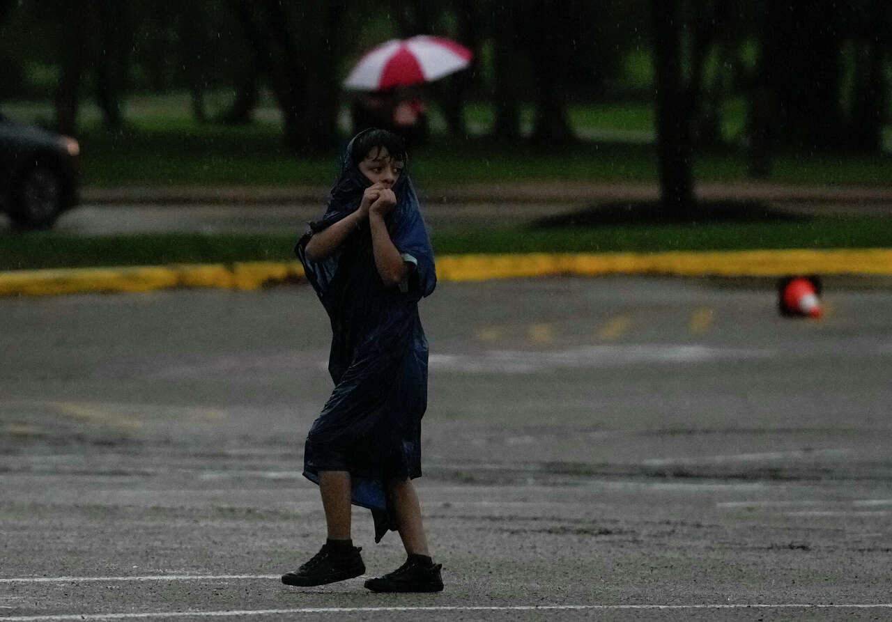 People try to get to their cars during a thunderstorm Friday in the Houston Zoo parking lot. Houston could see more rain early Sunday but storm chances diminish in the evening.