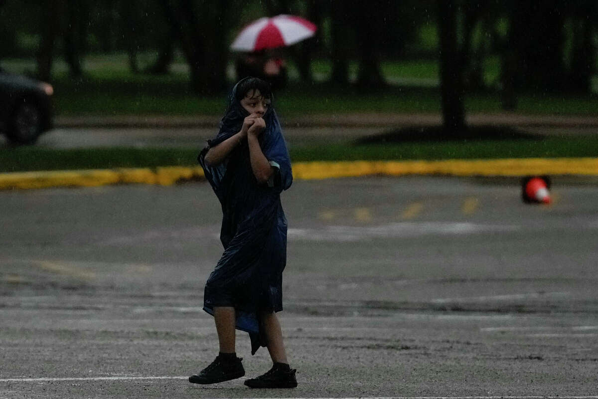 People try to get to their cars during a thunderstorm Friday in the Houston Zoo parking lot. Houston could see more rain early Sunday but storm chances diminish in the evening.