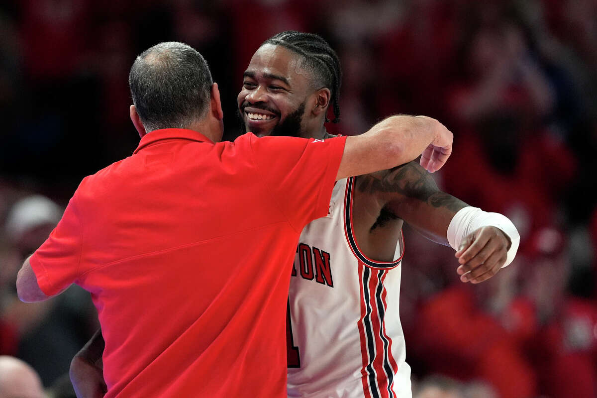 Houston's Jamal Shead, right, hugs coach Kelvin Sampson during the second half of an NCAA college basketball game against Kansas Saturday, March 9, 2024, in Houston.