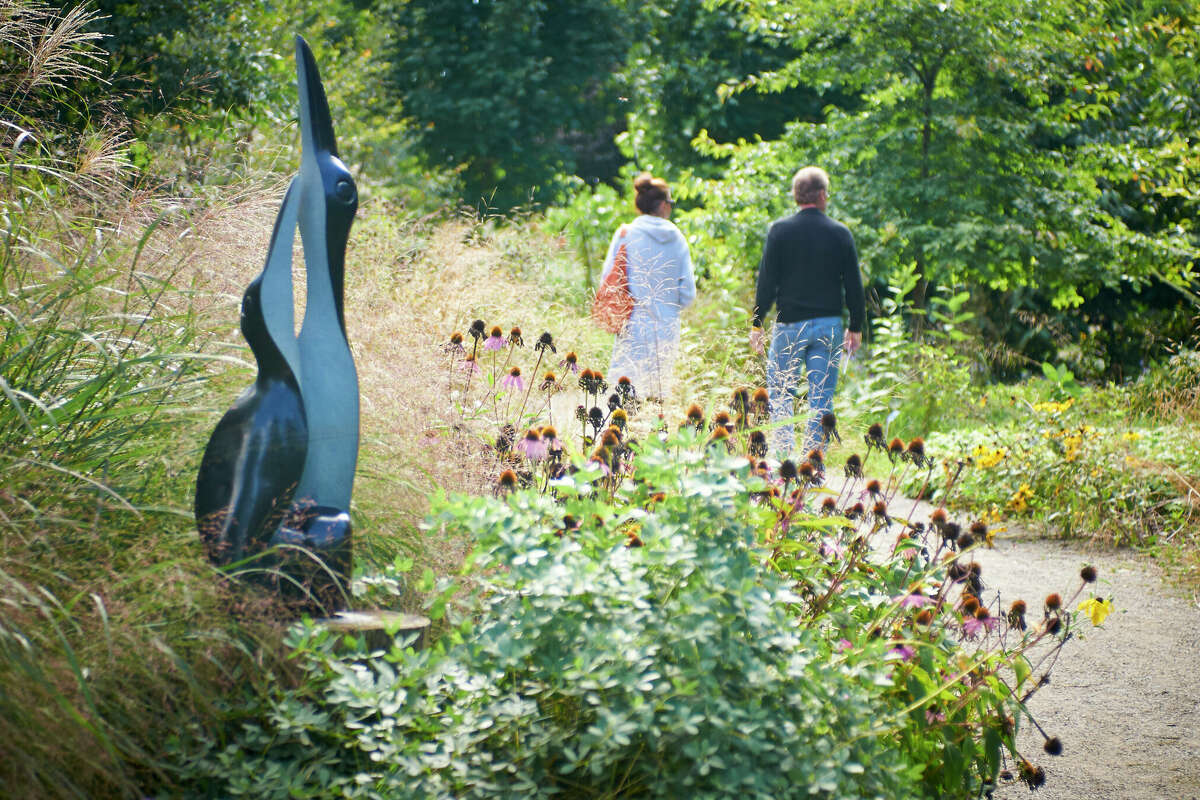 Visitors walk past a sculture of two birds as part of ZimScupt at the Houston Botanic Garden.