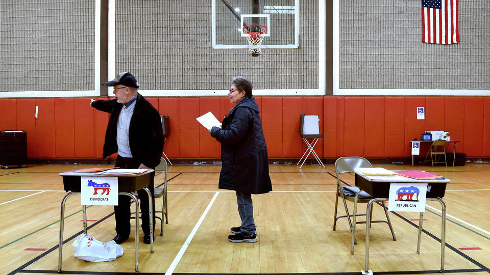 Ballot Clerk Don Russo, left, directs Andrea Jones where to take her completed ballot for the Presidential primary at Savin Rock Community School in West Haven on April 2, 2024.