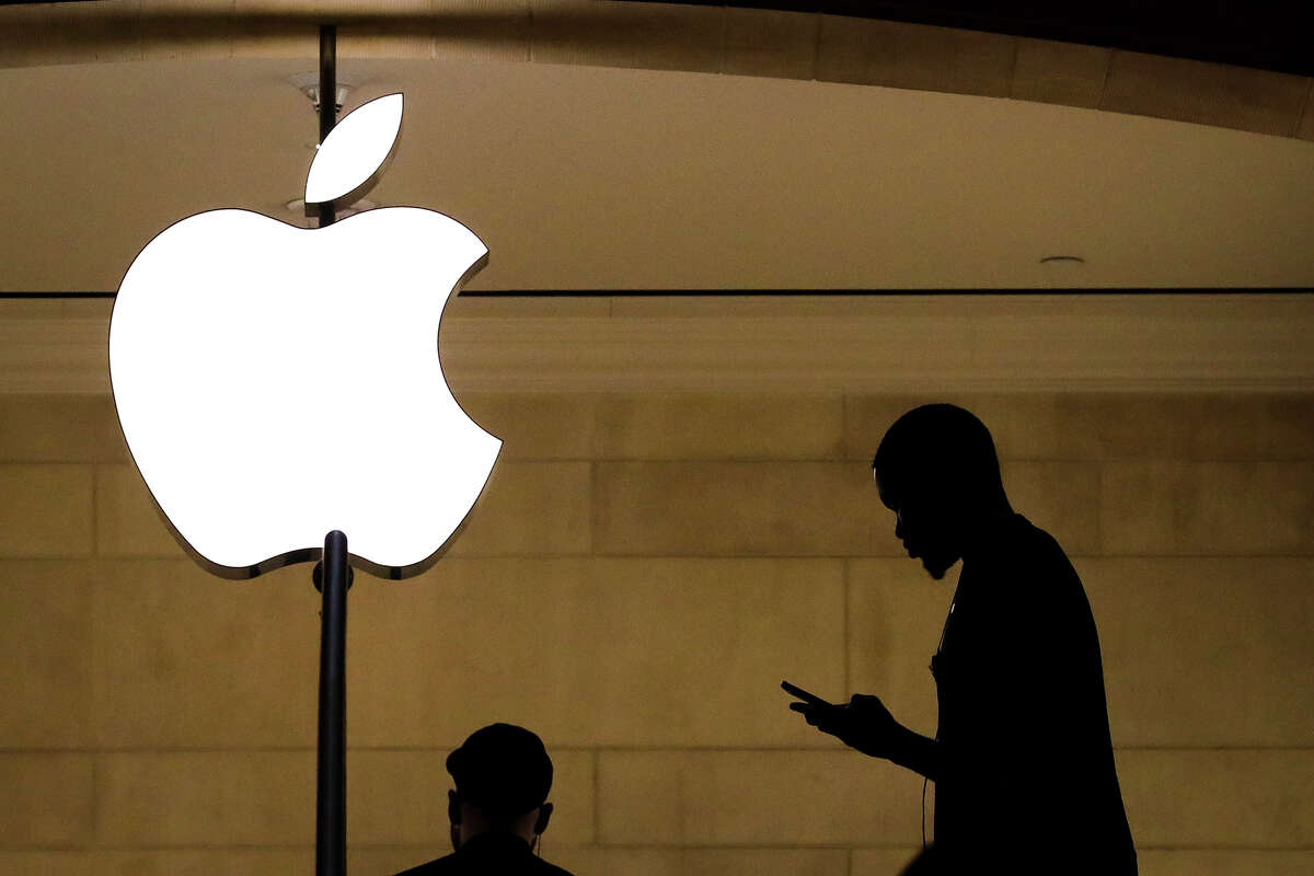 FILE: A man checks his phone in an Apple retail store. 