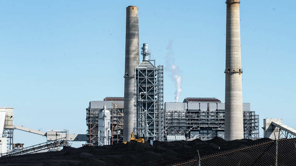 A pile of fuel coal sits adjacent to the stacks of the coal powered electric generation units at the WA Parish Generating Station Monday, Feb. 19, 2024 in Richmond. Solar panels supplied more electricity than coal-fired power plants to the power grid operated by the Electric Reliability Council of Texas for the first month ever March 2024.