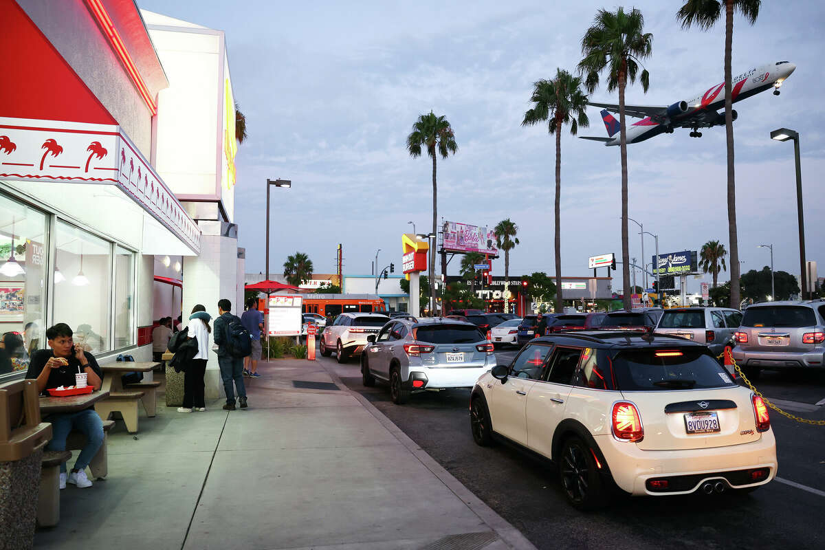 A Delta Airlines plane lands as people gather at In-N-Out Burger next to Los Angeles International Airport (LAX) on August 31, 2023 in Los Angeles, California. 