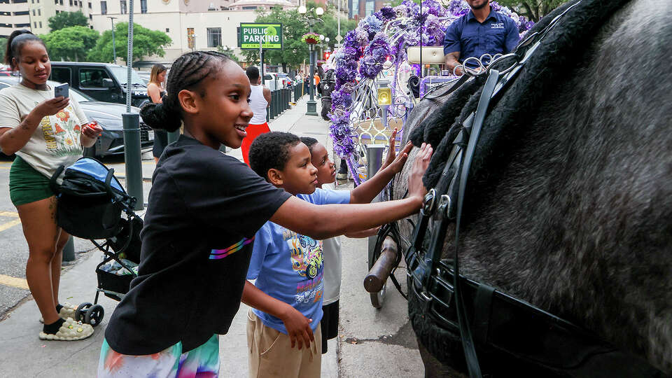 Ellyria Jackson, 11, from front left, Jeremy James, 8, and Chase James, 7, pet a horse named Reagan before going on a carriage ride in front of the Hard Rock Cafe on W. Crockett Street in downtown San Antonio on Wednesday, April 17, 2024.