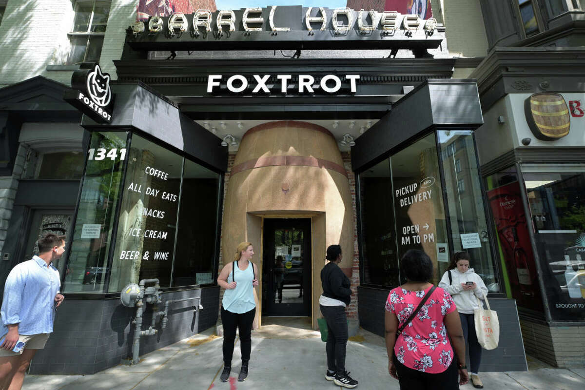 WASHINGTON, DC: - APRIL 23: People stop for a moment while passing by the Foxtrot location along 14th Street NW on Tuesday April 23, 2024 in Washington, DC. The chain is closing their DC locations as well as others in Illinois and Texas. (Photo by Matt McClain/The Washington Post via Getty Images)