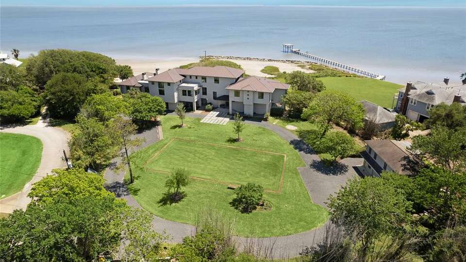 Spanning across two acres, the five-bedroom, six- and one-half bathroom single-family home sits bayside and includes a private beach and manicured grounds where a native marsh pond serves as a natural habitat for wildlife. 