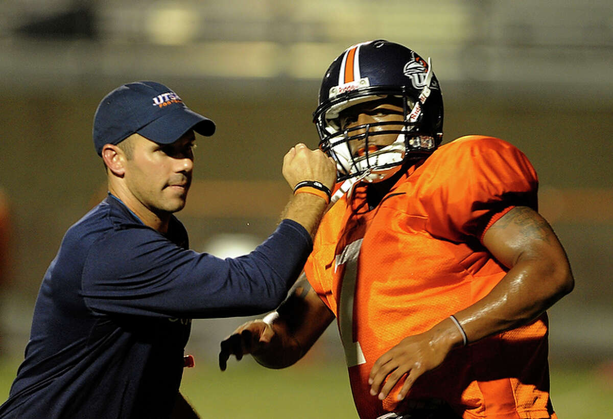 Assistant coach Travis Bush helps Kam Jones during practice.