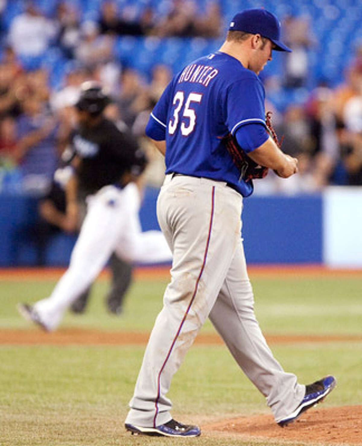 Tommy Hunter walks back to the mound as Toronto?s Vernon Wells rounds the bases after a three-run homer.