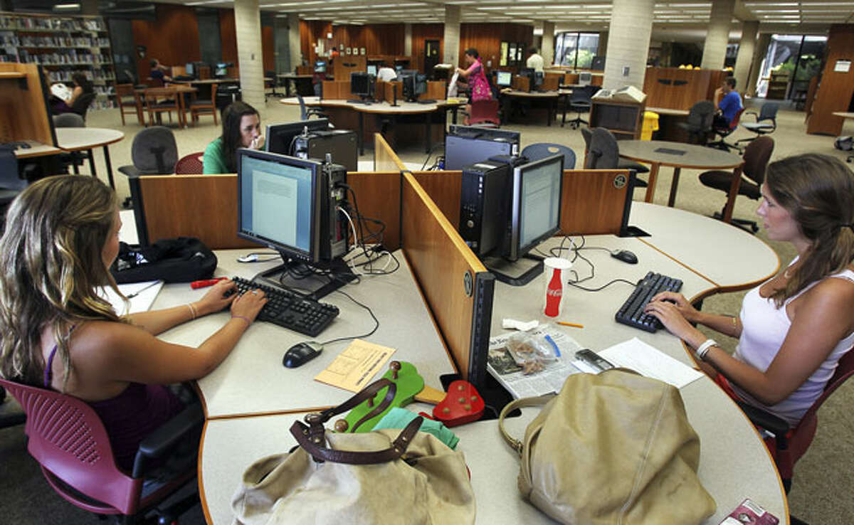Andree Gonzalez (from left), Moira Bedel and Hannah Harms occupy a computer table at Trinity University's Coates Library last week. While traditional research areas at the library are almost vacant, students use computers for study there.