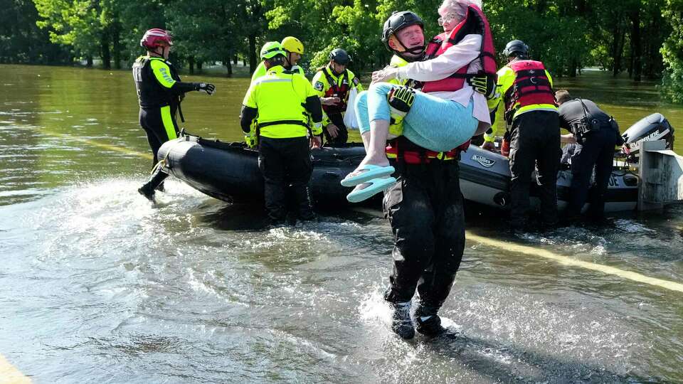 The Conroe firefighter Cody Leroy carries a resident evacuated in a boat by the CFD Rapid Intervention Team from her flooded home in the aftermath of a severe storm on Thursday, May 2, 2024 in Conroe. The rising water from the West Fork of the San Jacinto River, downstream from Lake Conroe, flooded homes and roads along FM2854.