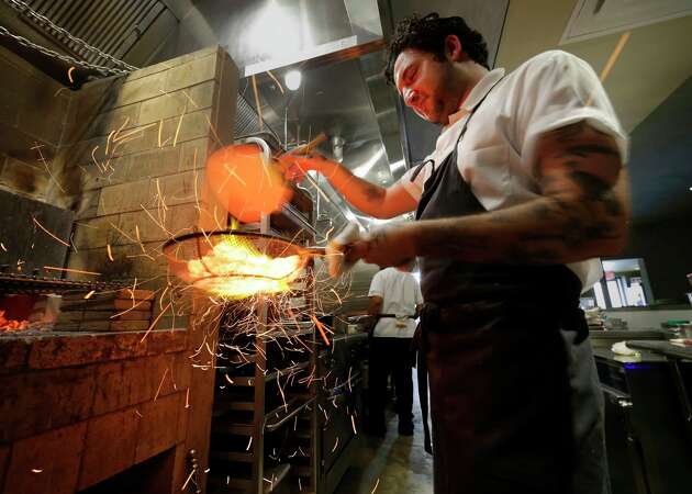 Sparks fly as Chef Max Lappe fans wood coals to raise the heat before using them to grill oysters at Baso, a new restaurant in The Heights Friday, May 3, 2024 in Houston.