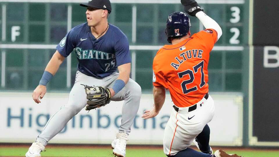 Houston Astros Jose Altuve (27) steals his 300th base against Seattle Mariners shortstop Dylan Moore (25) during the seventh inning of an MLB game at Minute Maid Park on Friday, May 3, 2024, in Houston.