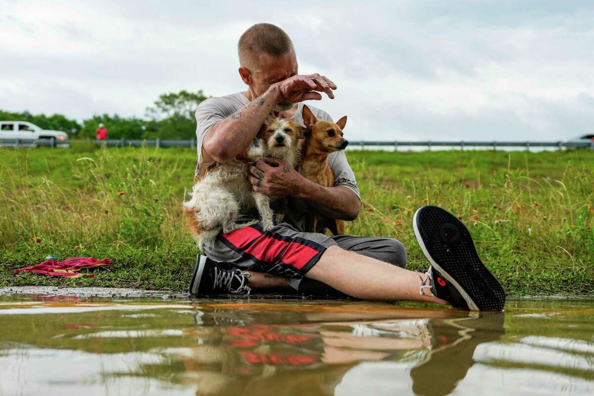 Tim McCanon sits on the road with his dogs after being rescued by the Community Fire Department during severe flooding on Friday, May 3, 2024, in New Caney, Texas. (Raquel Natalicchio/Houston Chronicle via AP)