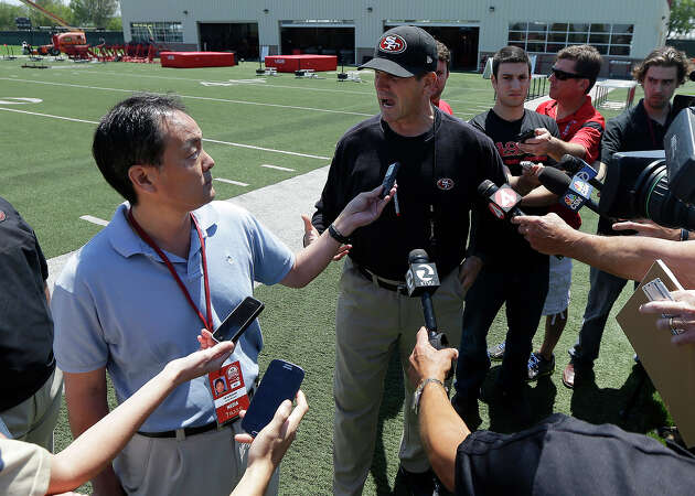FILE: San Francisco 49ers head coach Jim Harbaugh, center, answers questions from reporter Tim Kawakami, left, during the 49ers' NFL rookie camp in Santa Clara, Calif., Friday, May 23, 2014.