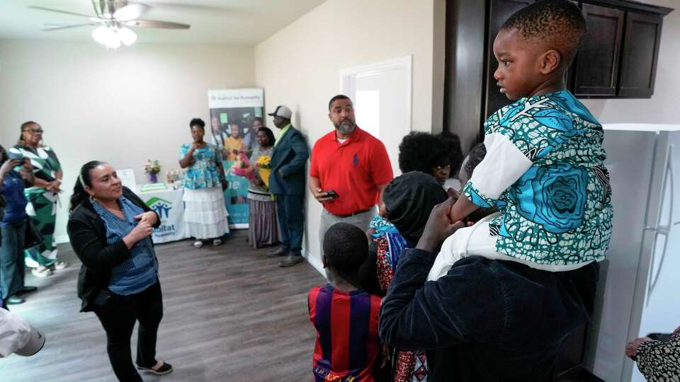 David Nshimirimana gets a bird's eye view of the Habitat for Humanity ceremony welcoming his grandparents into their new home in the Robin's Landing subdivision on Wednesday, May 8, 2024 in Houston. Developed by Houston Habitat for Humanity, Robins Landing, mixed-income, master-planned community on a 127-acre tract, featuring affordable housing in Northeast Houston.