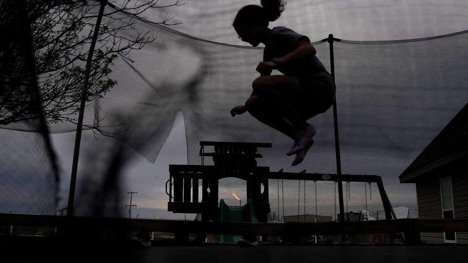 A flare burns near Vanessa and Victor Hinojos' home as their children play in the backyard on Wednesday, March 6, 2024 in Odessa. on Wednesday, March 6, 2024 in Odessa.