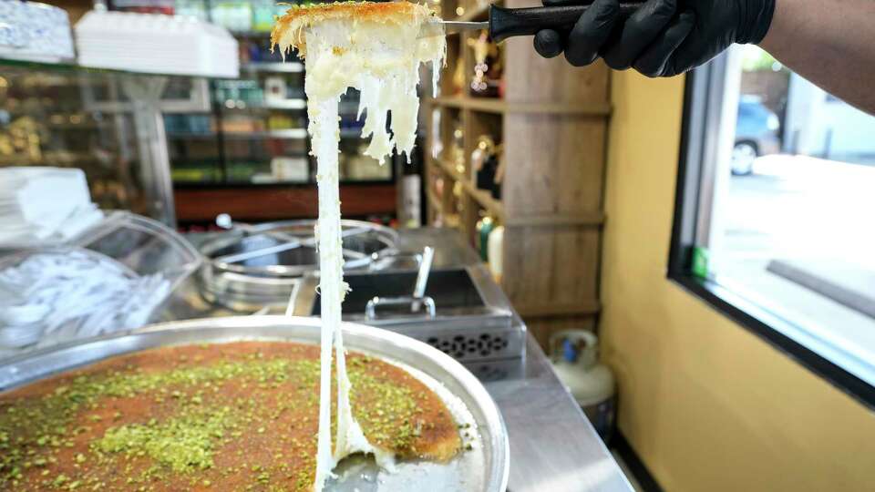Mohamad Iweinat cuts a piece of Knafeh at Royal Roastery on Friday, May 10, 2024 in Houston. Knafeh is a traditional Arabic dessert, made with spun pastry called kataifi, soaked in a sweet, sugar-based syrup called attar, and typically layered with cheese, or with other ingredients such as clotted cream, pistachio or nuts.