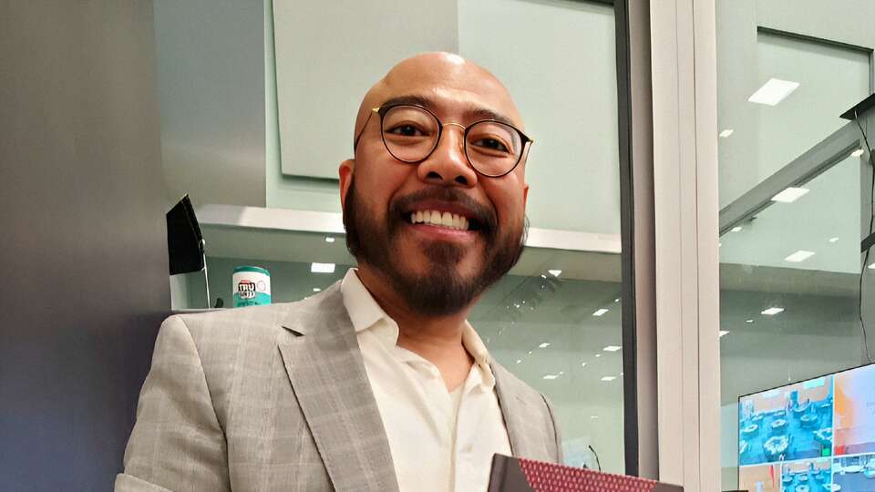 Zen Zheng stands with a photo of his book 'The Significance of Chinatown Development to a Multicultural America: An Exploration of the Houston Chinatowns.'