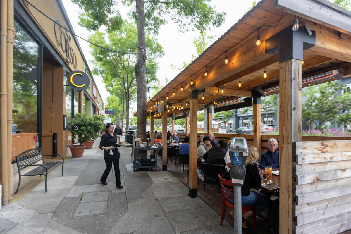 Server Claudia Solorio brings out the food orders to customers dining in the parklet in front of Via del Corso in Berkeley, Calif. on May 16, 2024. Berkeley is implementing a new rule to allow businesses to keep their parklets by charging them an annual fee.