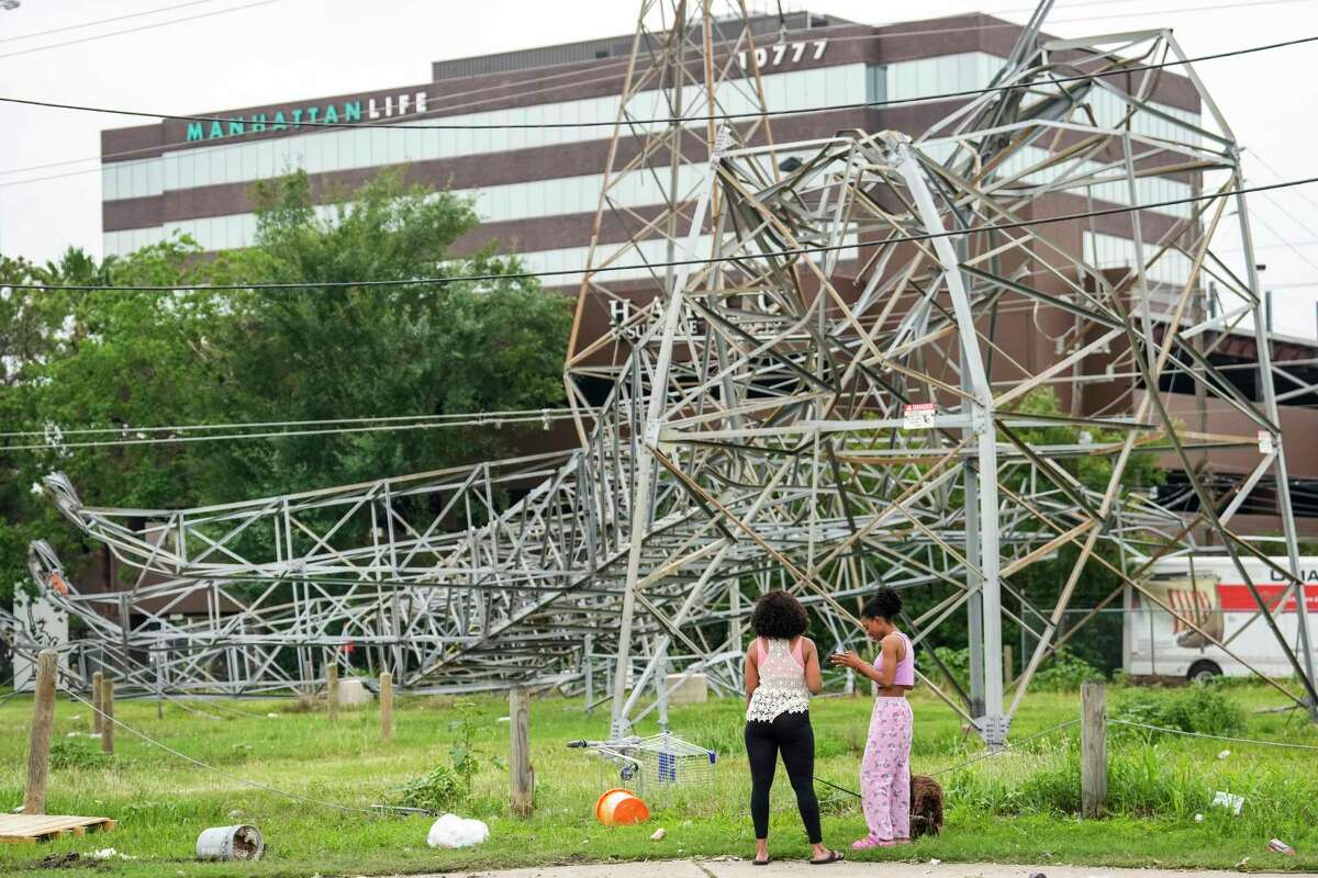 Emilia Kobina, left, and Denise Kobina take a look at a fallen transmission line tower along the US 290 feeder road in the aftermath of a severe storm on Friday, May 17, 2024 in Houston. Fast-moving thunderstorms pummeled southeastern Texas for the second time this month, killing at least four people, blowing out windows in high-rise buildings, downing trees and knocking out power to more than 900,000 homes and businesses in the Houston area.