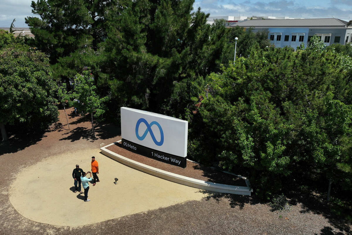 People gather in front of a sign posted at Meta headquarters on July 07, 2023 in Menlo Park, California. The company once known as Facebook will watch one of its former executives go to prison for fraud.