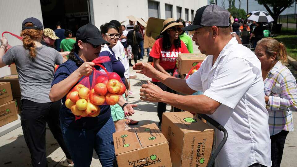 Jose Guzman, front right, gets food and water in the aftermath of a destructive storm Saturday, May 18, 2024, at Sam Houston Math, Science and Technology Center in Houston. Guzman lives with his 75-year-old mom and his daughter. 