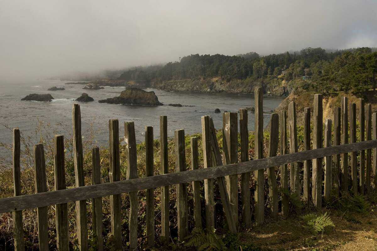 A wooden picket fence along rugged coastline highway north of town is seen in this Mendocino County landscape photo.